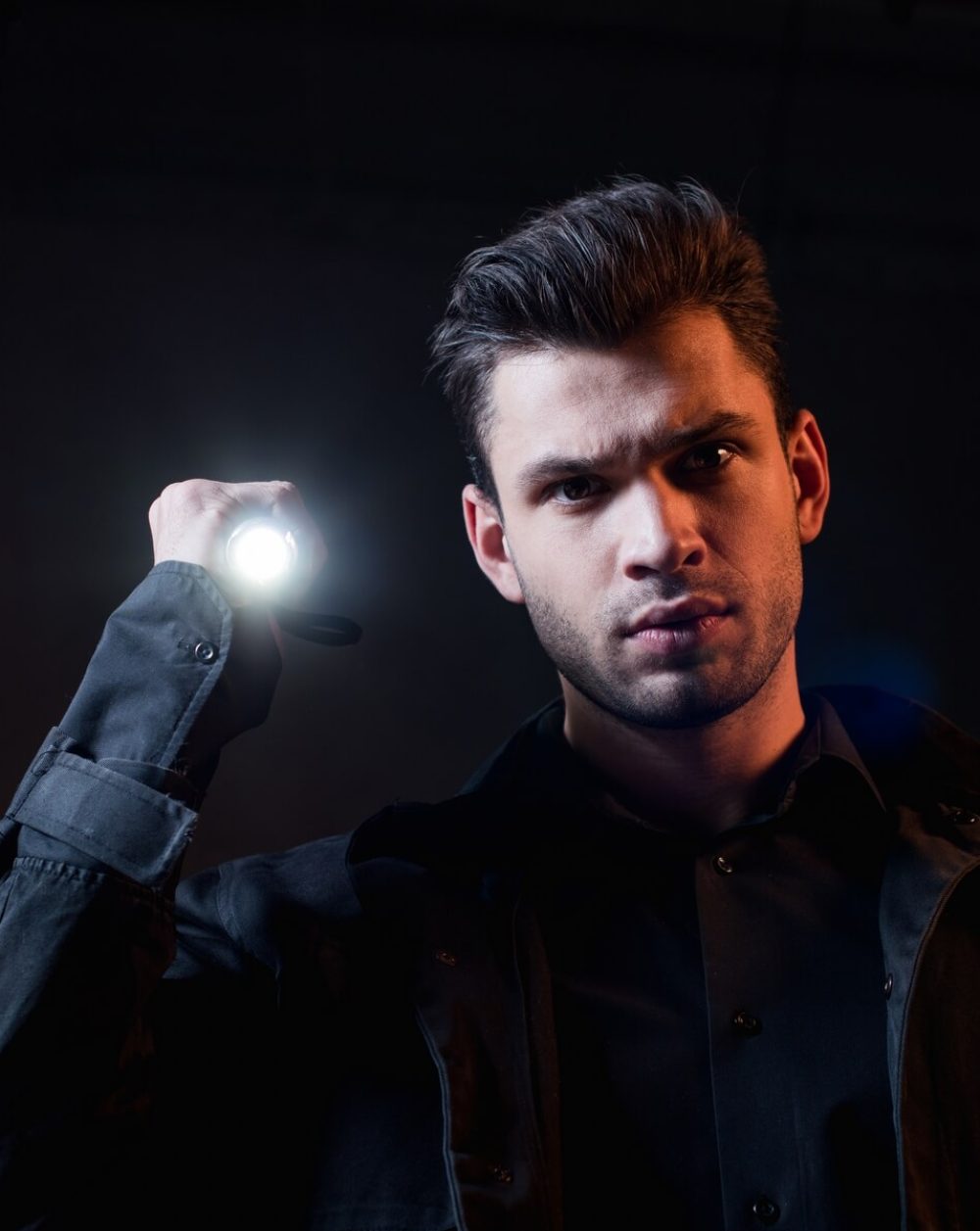 guard-in-uniform-holding-flashlight-and-looking-at-Q5SYJTN